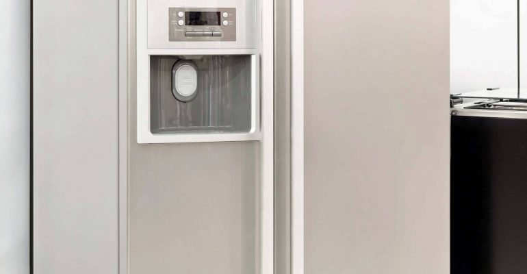 A stainless steel refrigerator is next to a washer and dryer.